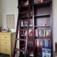 Donkerrode houten bibliotheekkast met trap