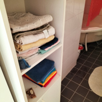 Hoge witte badkamerkastje met open vakken en deuren