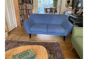 Blauwe tweezitsbank op poten retro