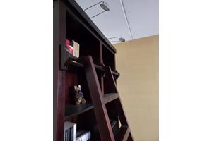 Donkerrode houten bibliotheekkast met trap