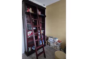 Donkerrode houten bibliotheekkast met trap