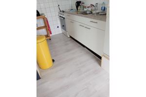Een mooie, lichtgrijze laminaatvloer met ondertapijt