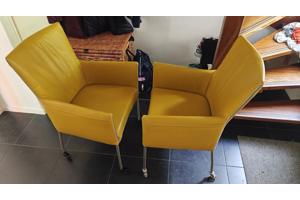 Twee gele leren stoelen met wieltjes