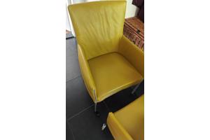 Twee gele leren stoelen met wieltjes
