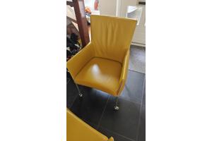 Twee gele leren stoelen met wieltjes