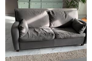 Grijs stoffen twee-zits bankje.