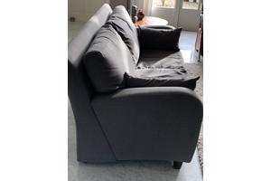 Grijs stoffen twee-zits bankje.