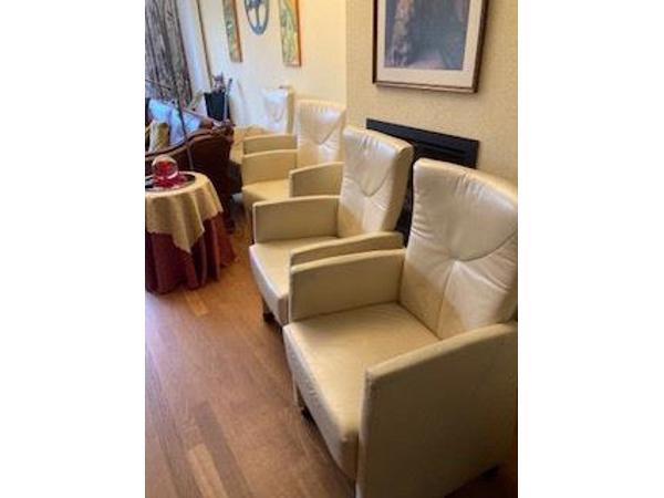 Vier crèmekleurige clubfauteultjes met wieltjes