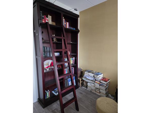 Donkerrode houten bibliotheekkast met trap
