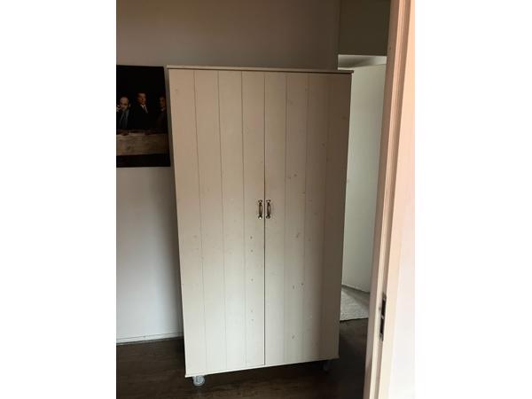 Mooie witte kinder kledingkast op wieltjes.