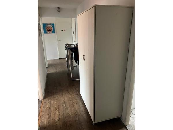 Mooie witte kinder kledingkast op wieltjes.