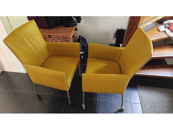Twee gele leren stoelen met wieltjes