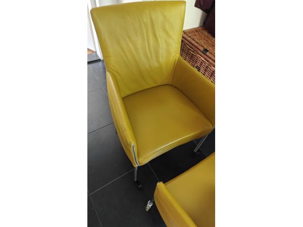 Twee gele leren stoelen met wieltjes