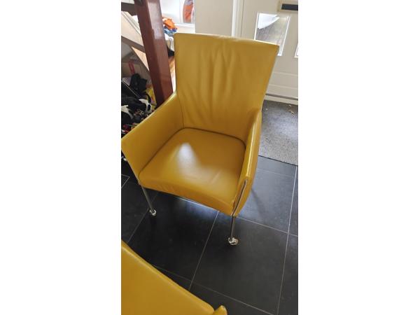 Twee gele leren stoelen met wieltjes
