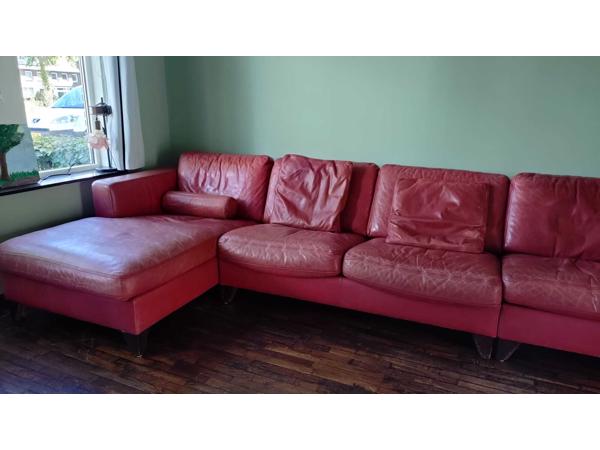 Grote rode leren bank met chaise longue. Kan ook in drie losse delen worden neergezet.